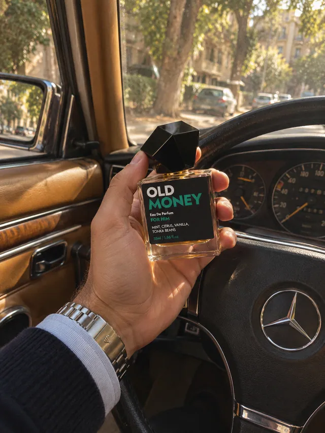 Old Money in a man’s hand at the wheel of a classic car